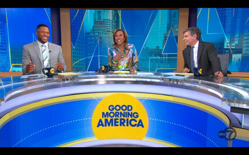 Robin Roberts reacts to a surprise wink from co-anchor Michael Strahan on Good Morning America with George Stephanopoulos