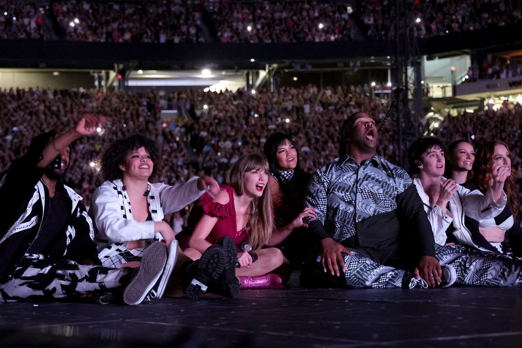 Taylor and her giant posse of dancers curled up on the runway to watch the video premiere of "Karma" (feat. Ice Spice)