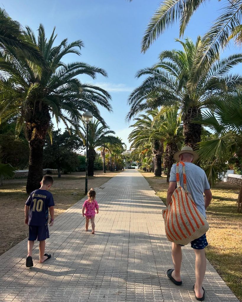 grandfather with two grandchildren walking down path 