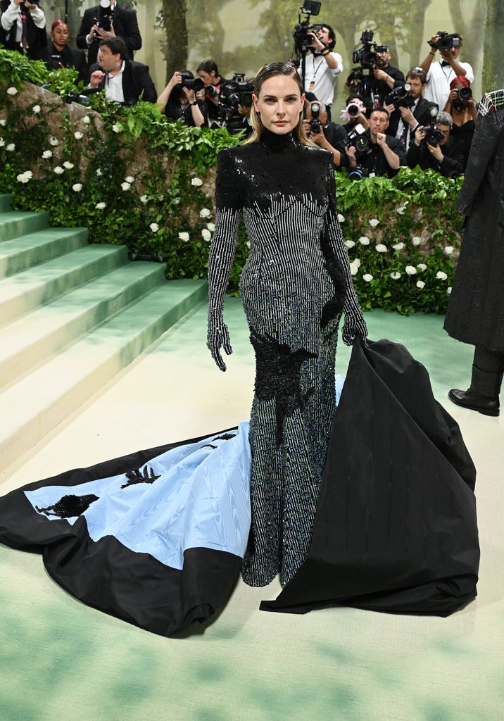 At the Met Gala, Rebecca stuns in a beaded black-and-silver gown with a dramatic light blue cape 