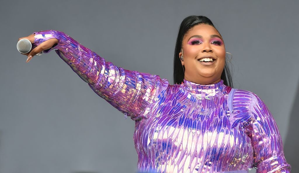 Lizzo wearing a holographic purple bodysuit with pink eyeshadow 