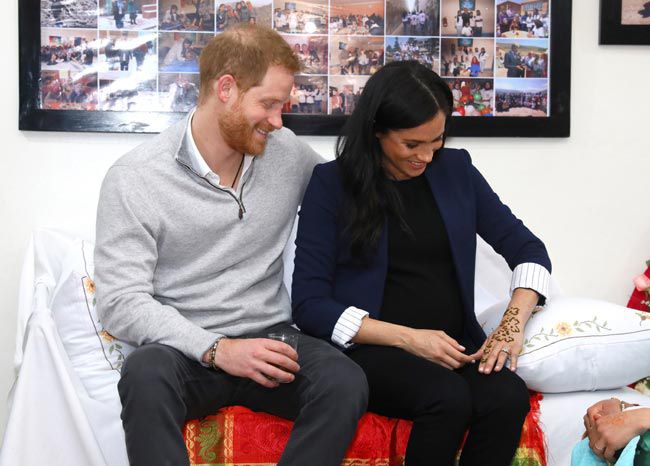 Prince Harry and Meghan Markle looking at her henna tattoo