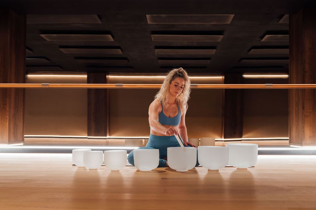 Woman playing sound bowls in a blue crop top