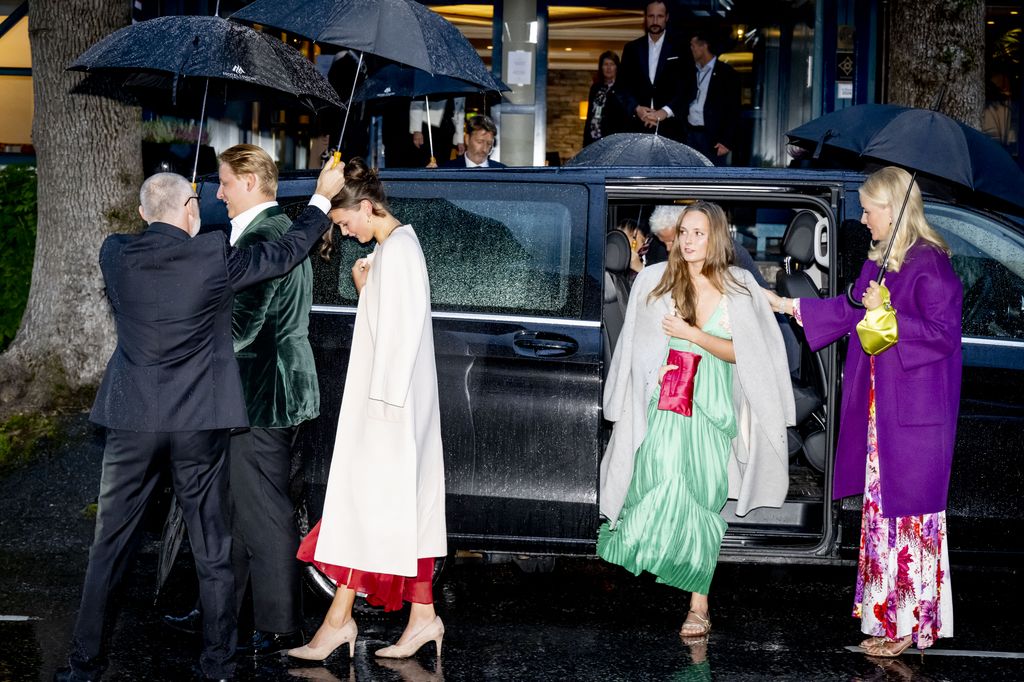 Prince Sverre and Amalie Giaever Macleod under umbrellas walking away from Princess Ingrid Alexandra and Crown Princess Mette-Marit