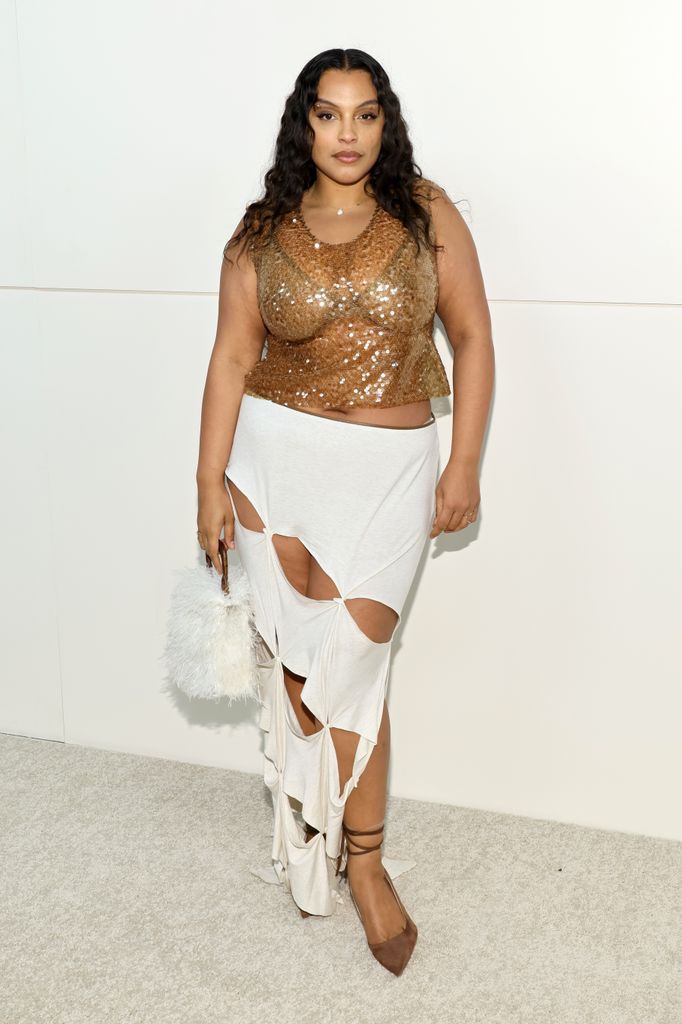 Paloma Elsesser wears a bronze sequin top and white slashed skirt with a feathered bag at a 2023 fashion event.