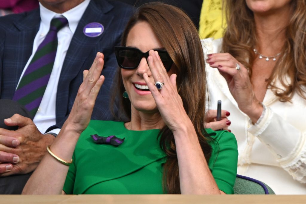 Kate Middleton wearing a green dress and putting her hands over her face at Wimbledon