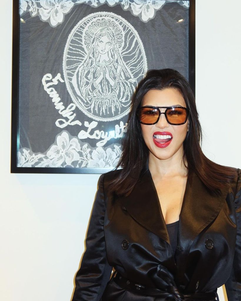 Kourtney Kardashian poses in front of her framed veil