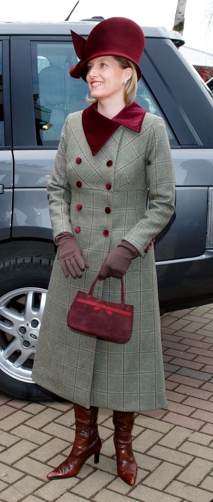Sophie in coat dress with big burgundy hat and boots