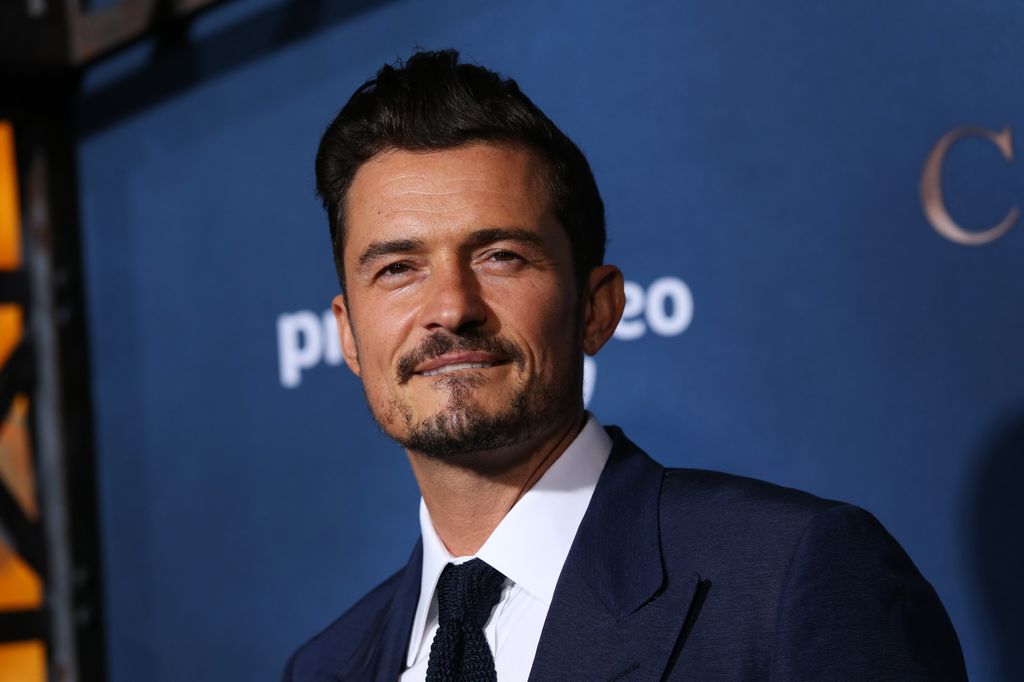 Orlando Bloom wears a navy suit as he hits the red carpet