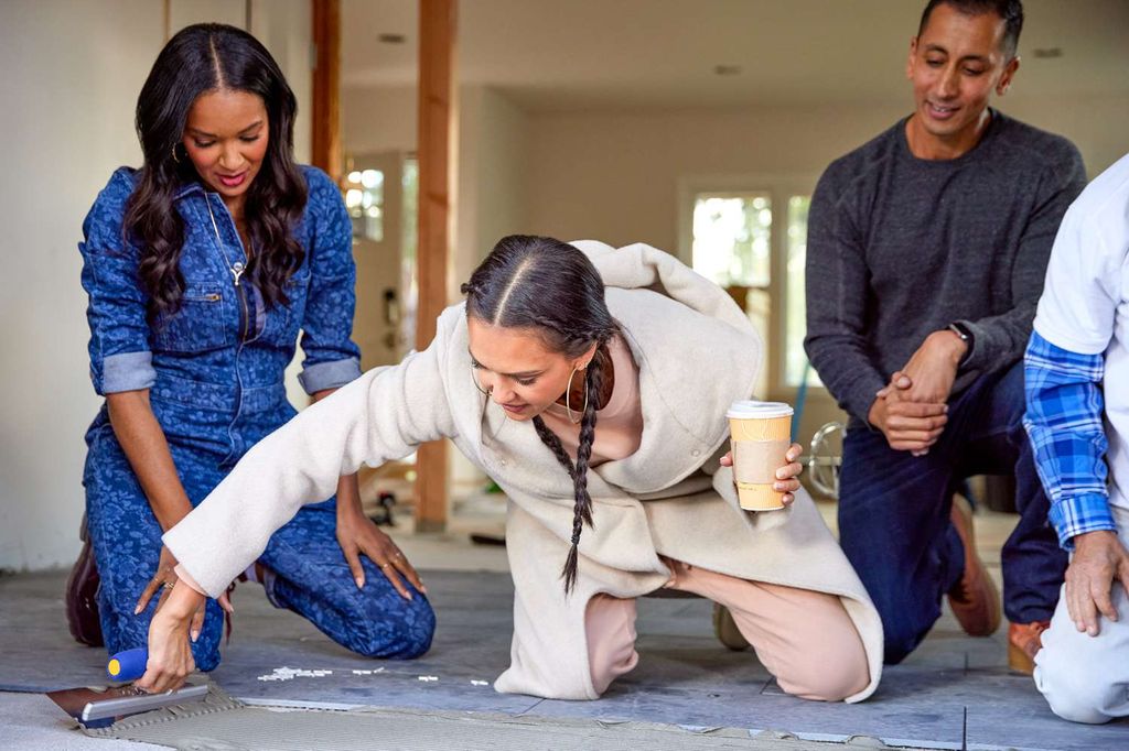 Lizzy Mathis (left) watches as Jessica Alba lays cement 