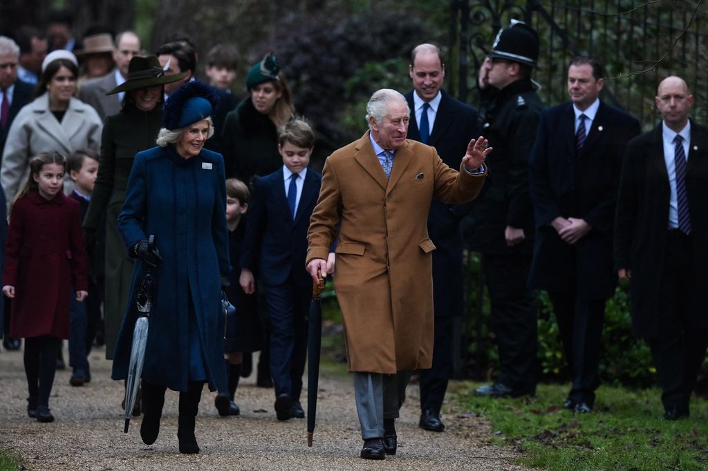 ritain's King Charles III (R) flanked by Britain's Camilla, Queen Consort (L) waves to members of the public as he arrives for the Royal Family's traditional Christmas Day service at St Mary Magdalene Church in Sandringham, Norfolk