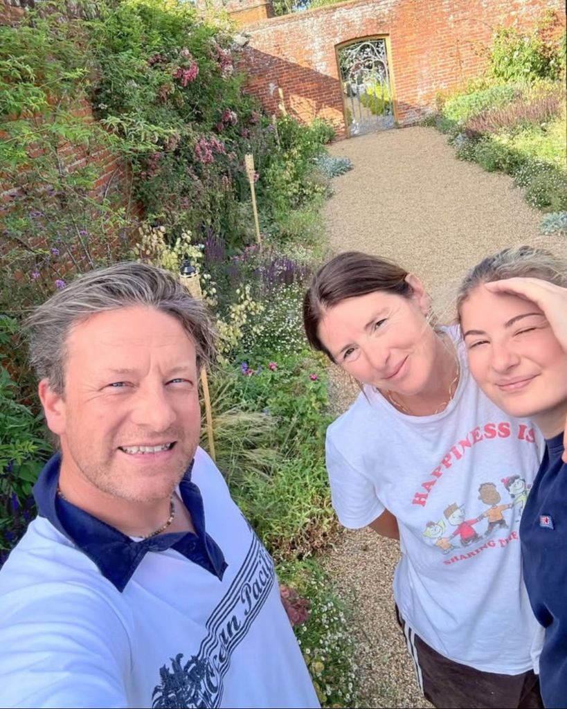 Jamie Oliver takes a selfie next to his wife, Jools and daughter Poppy with their garden in the background