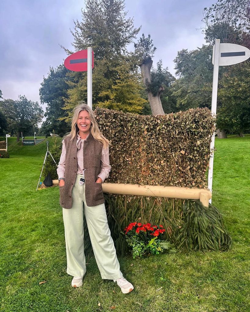 Marina Fogle in country attire smiling in front of a horse jump