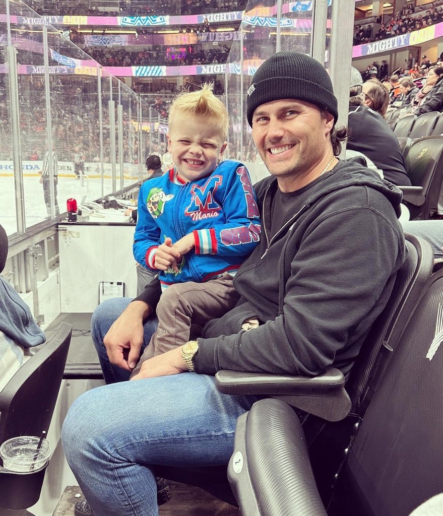 Photo shared by Christina Hall on Instagram November 5 2023 of her husband Josh Hall with her son Hudson sitting on his lap while at a hockey game
