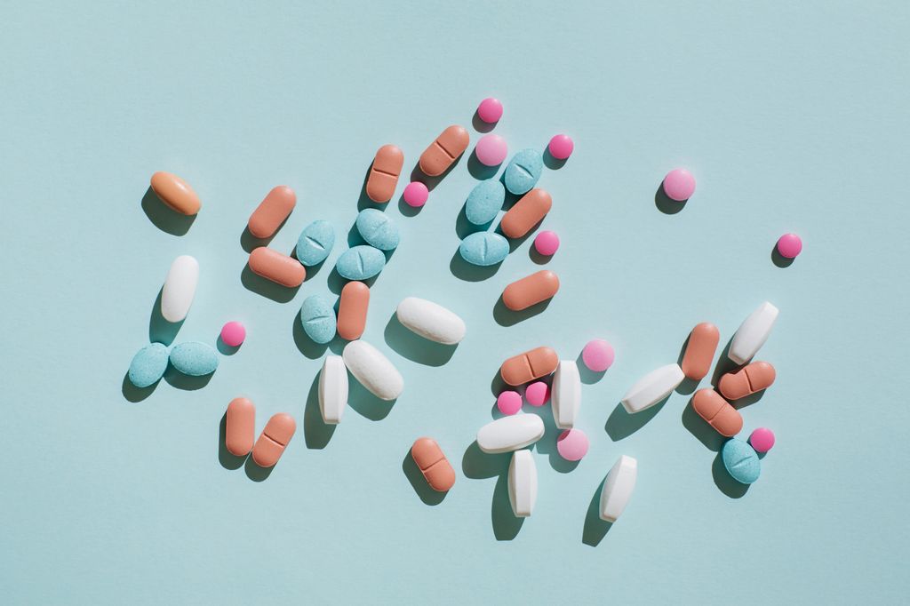 Colorful pills and capsules on blue background. Minimal medical concept. Flat lay, top view.