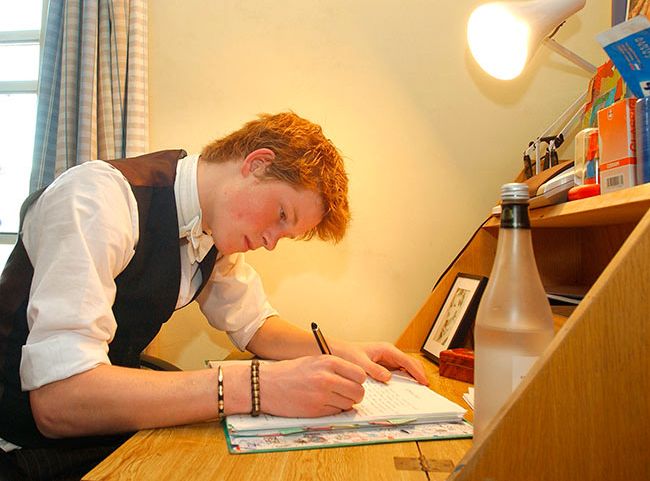 Prince Harry in Eton bedroom writing at desk