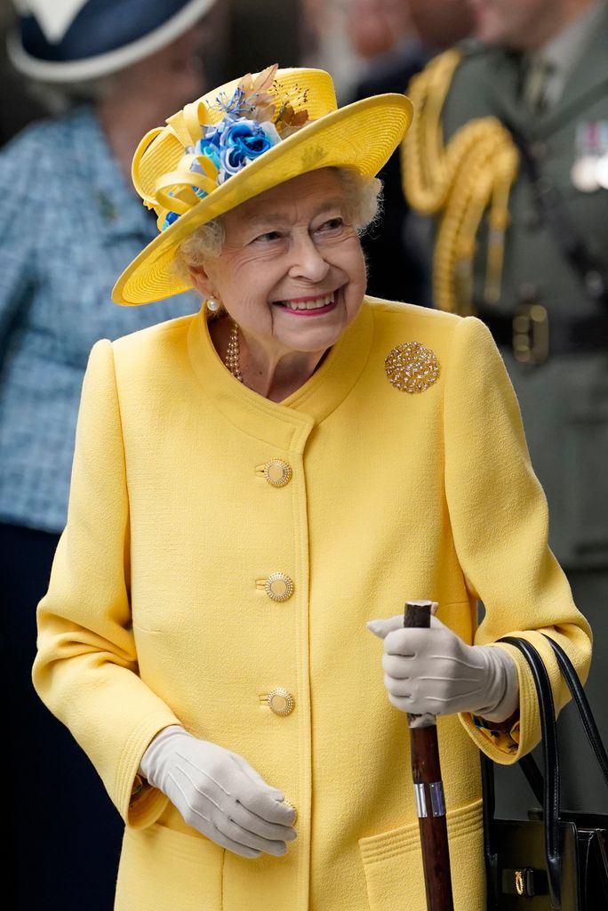 Queen Elizabeth II smiling in a yellow coat and hat