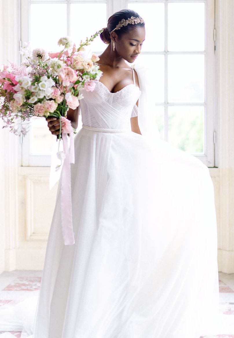 Bride in a corset wedding dress holding a pink bouquet
