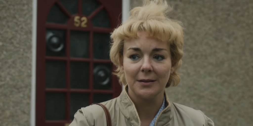 woman with short blonde hair outside house