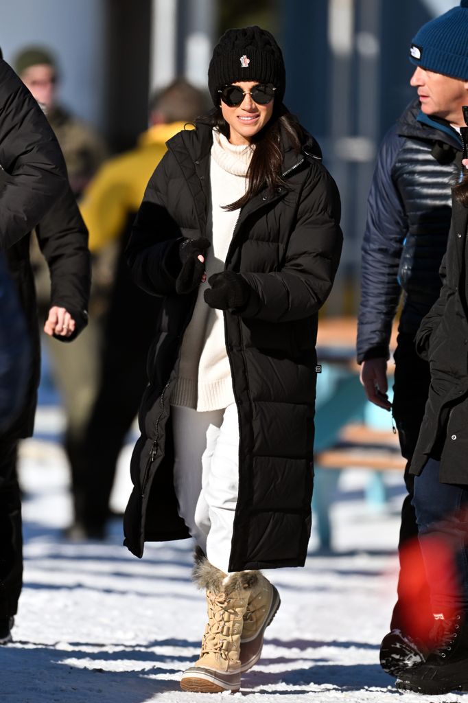 Meghan, Duchess of Sussex at the Invictus Games 2024 wearing a long black coat, white jumper, white jeans and brown knee high hiking boots with fluffy trim