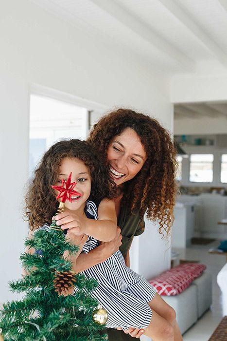 A mum and a daughter decorating a Christmas tree together