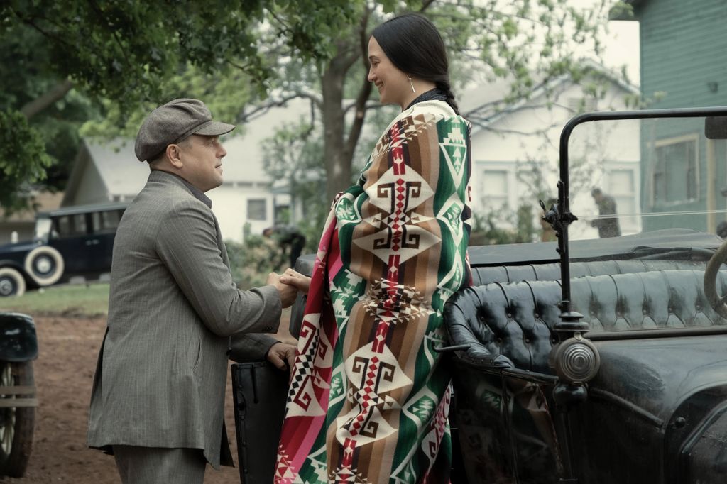 Leonardo DiCaprio as Ernest Burkhart helps Lily Gladstone as Mollie Burkhart into a car