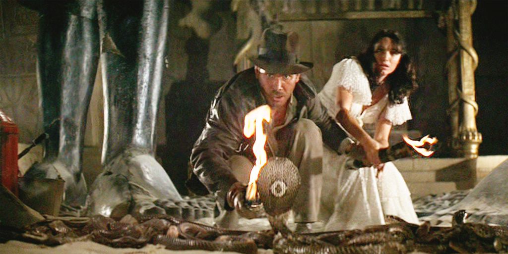 The movie: Indiana Jones and the Raiders of the Lost Ark , (aka: "Raiders of the Lost Ark"), directed by Steven Spielberg.  Seen here, Harrison Ford as Indiana Jones facing a cobra snake in the Well of the Souls chamber. In background, Karen Allen as Marion Ravenwood