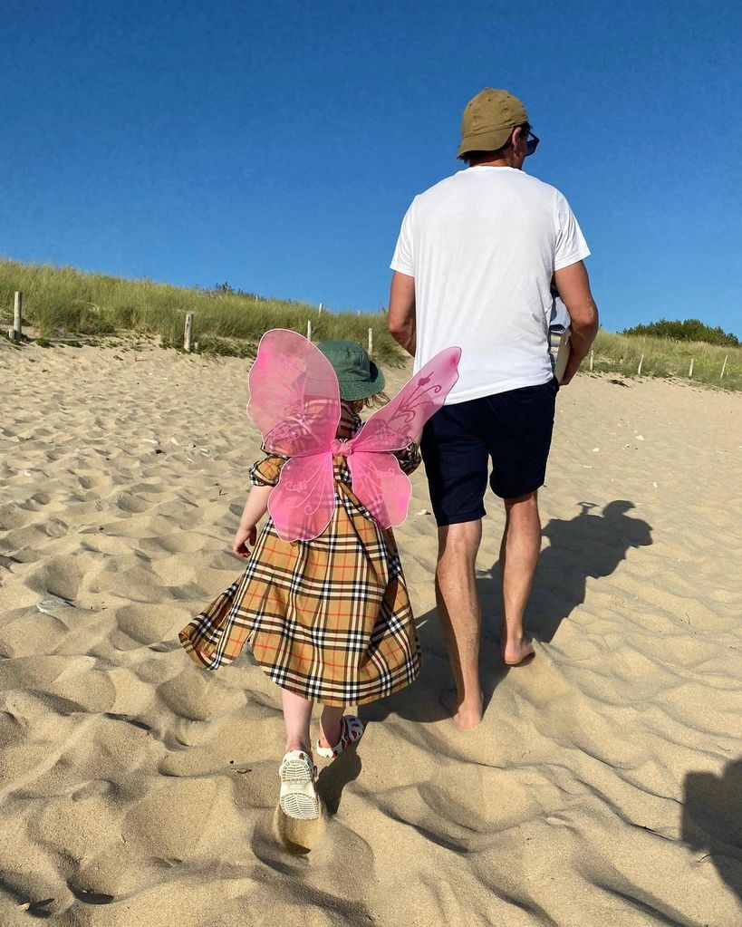 Angela's husband Roy walking on beach with daughter