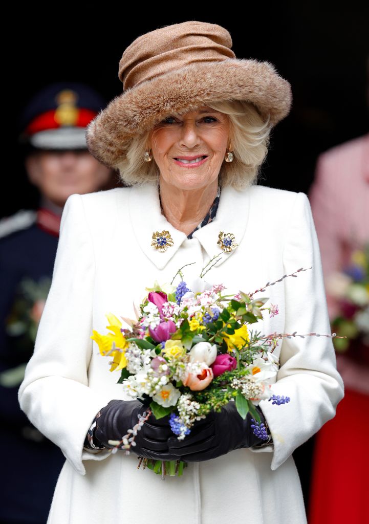 woman holding bunch of flowers in white coat and fur hat 