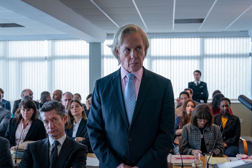 man in suit standing in front of busy room