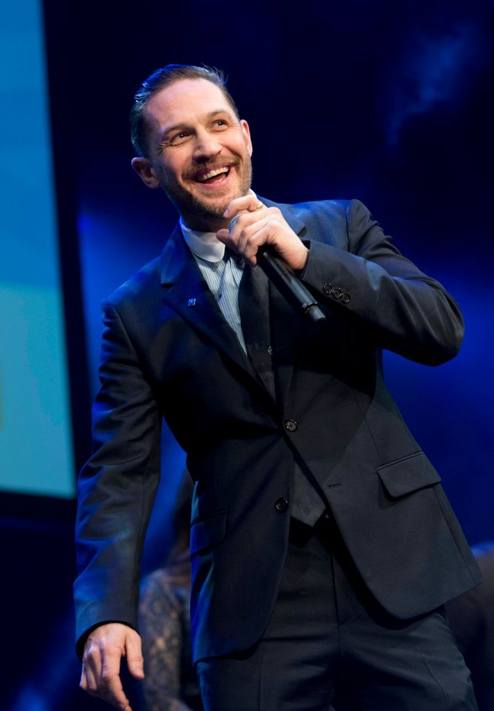 Tom Hardy smiling while wearing a suit