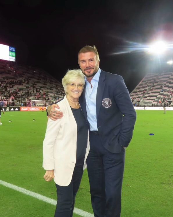 Sandra Beckham with david beckham in suit on football pitch