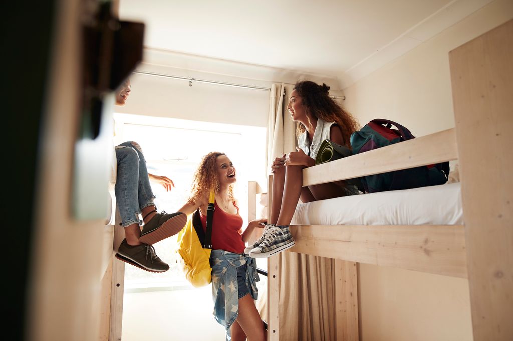 Young women having a good time and hanging out, at youth hostel with bunk beds