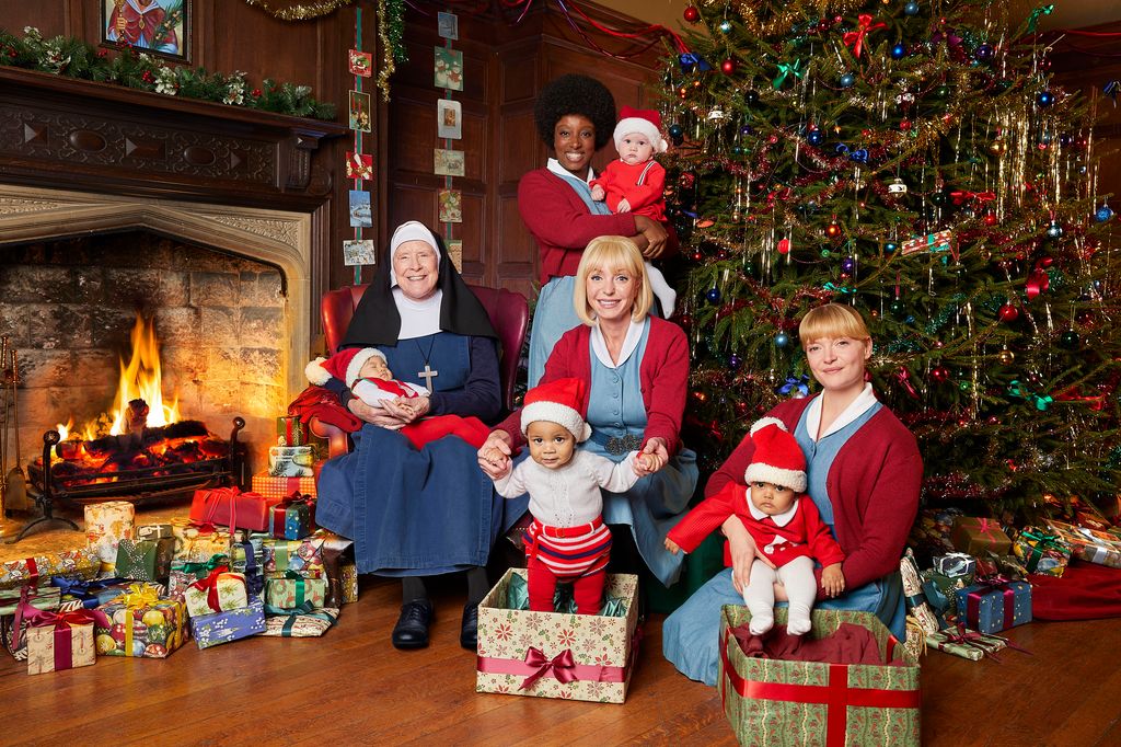group of midwives sitting by christmas tree with babies
