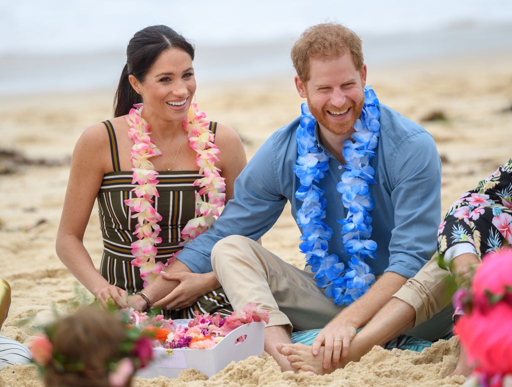 harry and meghan sitting on beach in australia