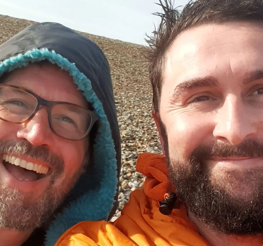 Alistair Appleton and his husband on a stone beach