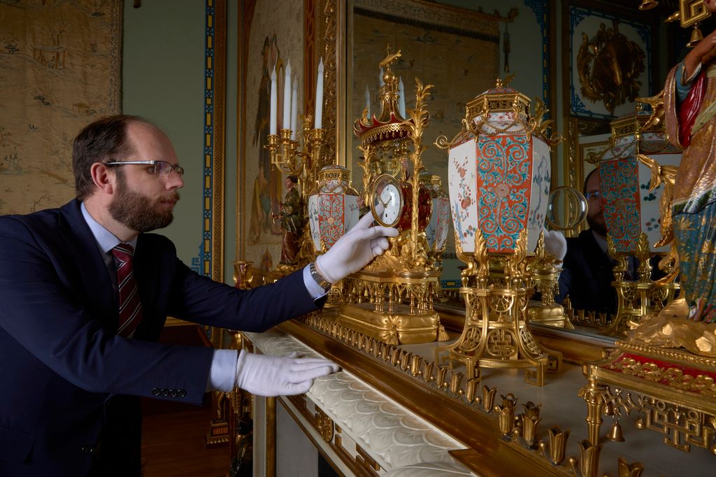 A Horological Conservator adjusts a late-18th-century French mantel clock in the Centre Room in the East Wing of Buckingham Palace