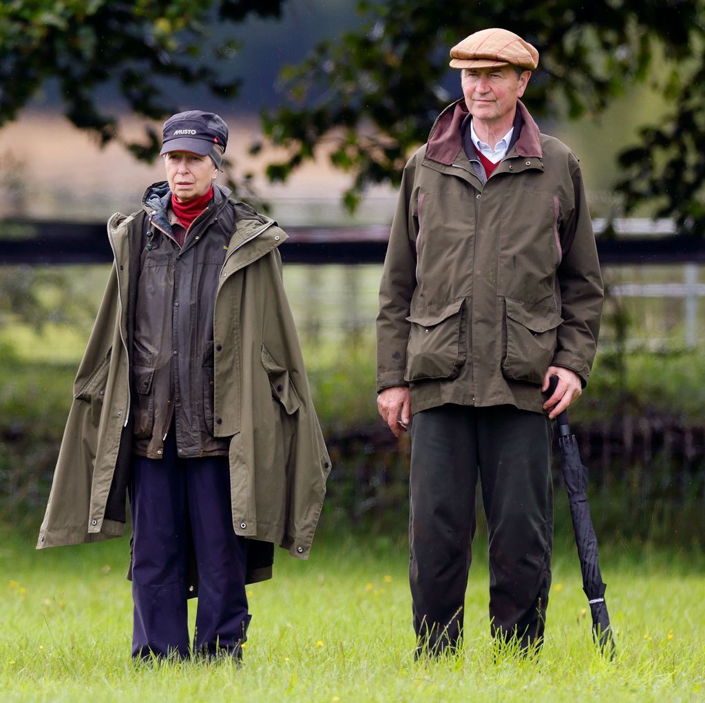 couple standing on grass in green coats and hats