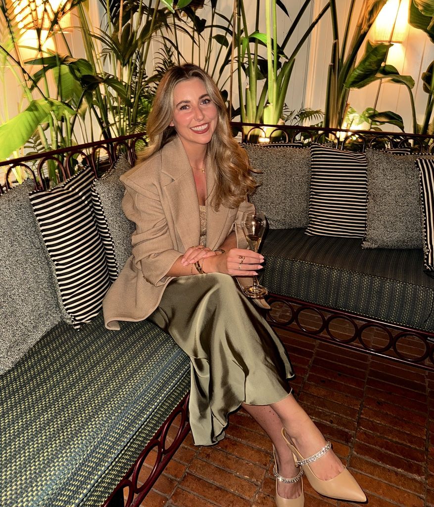 Woman wearing a silky skirt smiling with a drink
