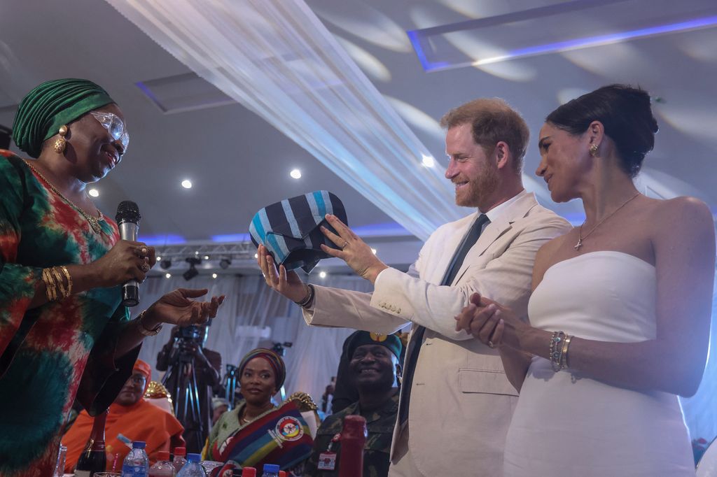 Prince Harry and Meghan Markle receive a traditional outfit made in Nigeria as they attend lunch at the Nigerian Defence Headquarters in Abuja