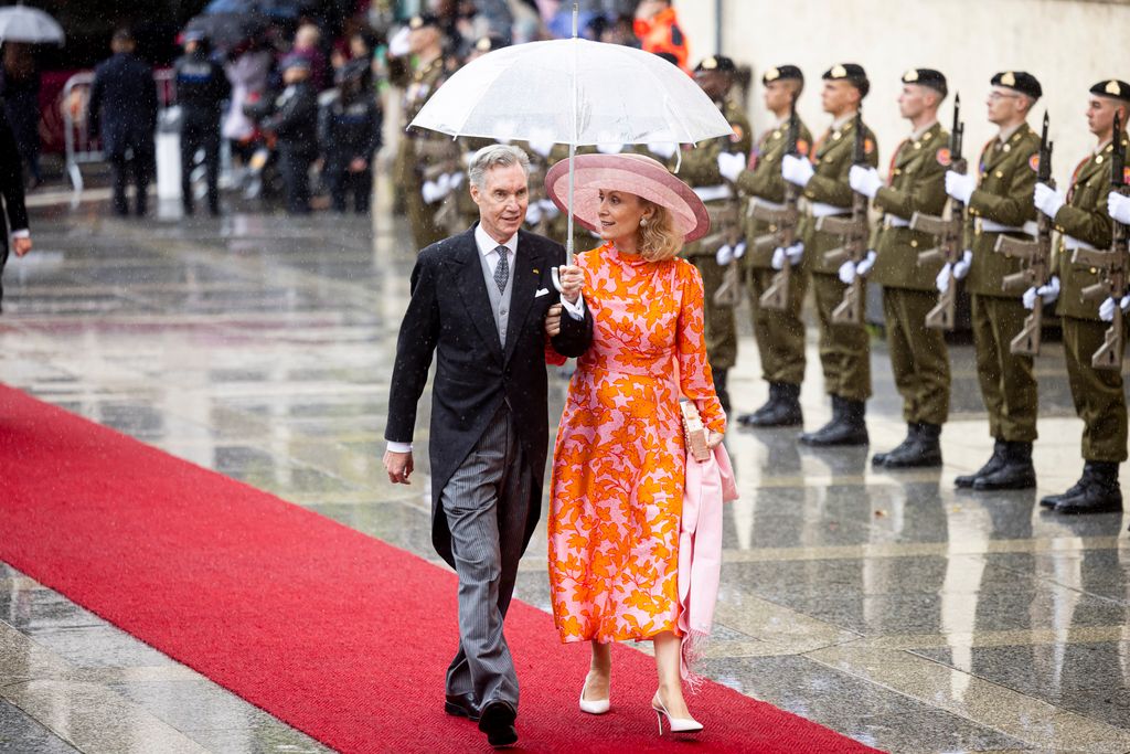 Prince Guillaume of Luxembourg and Princess Sibilla of Luxembourg under umbrella walking up red carpet