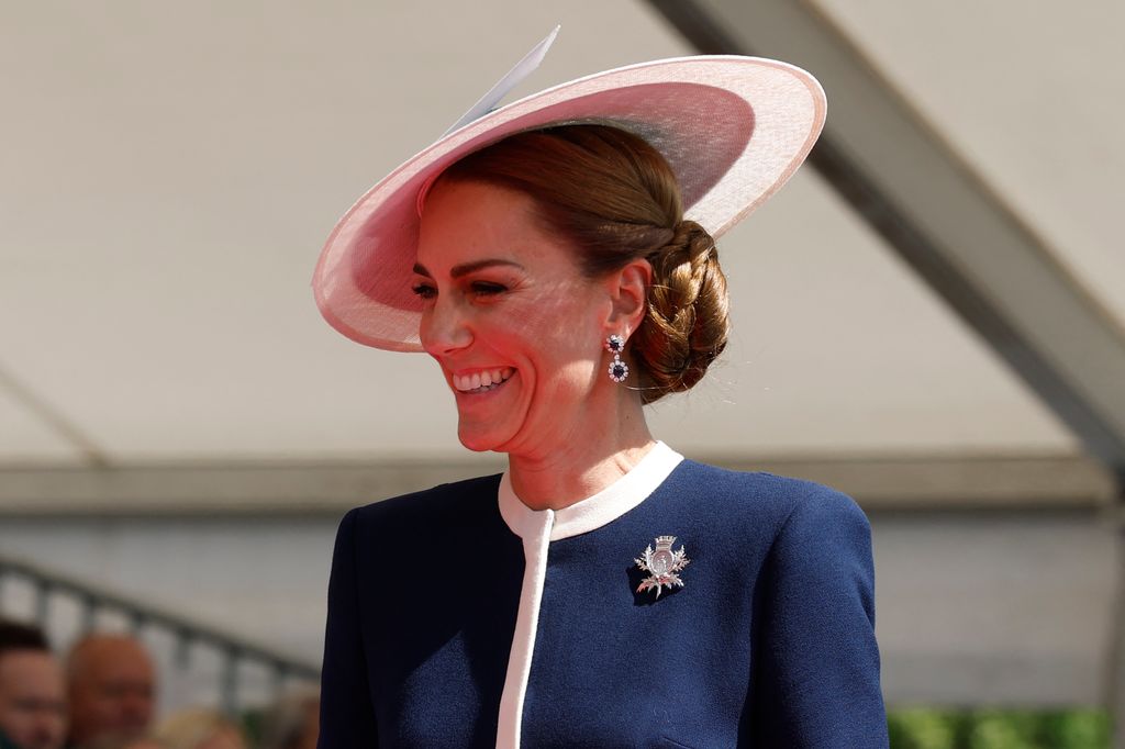 Headshot of the Princess of Wales smiling wearing navy dress and matching hat while on engagement in Glasgow
