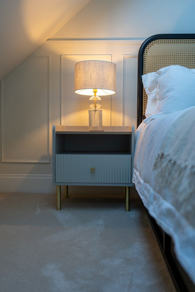 A bed with bedside table with lamp