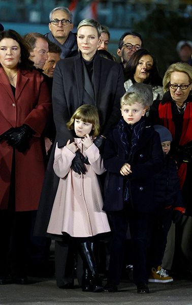 Princess Charlene putting her arms around Princess Gabriella with Prince Jacques stood next to them