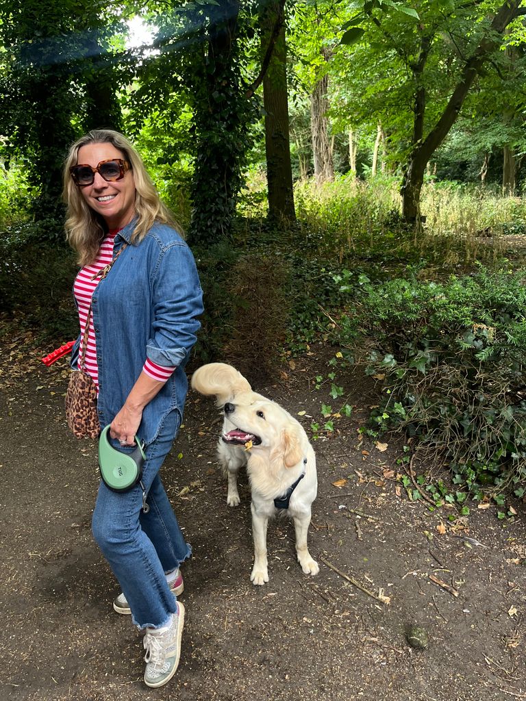 Woman smiling in denim walking a dog in the forest