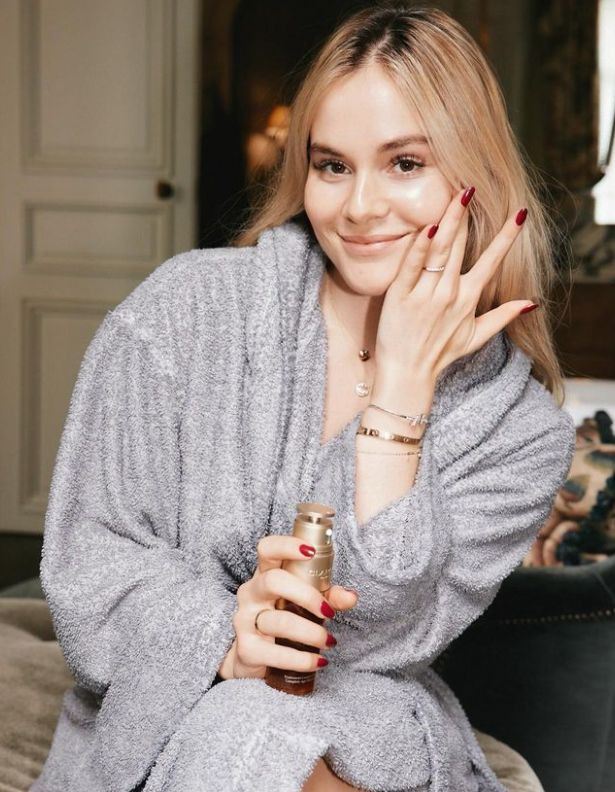 Holly Ramsay applying cream on her face while in a grey dressing gown