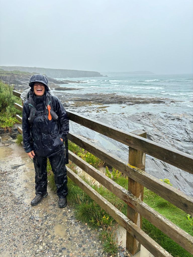 woman standing on a cliff edge in waterproof clothes in the rain 