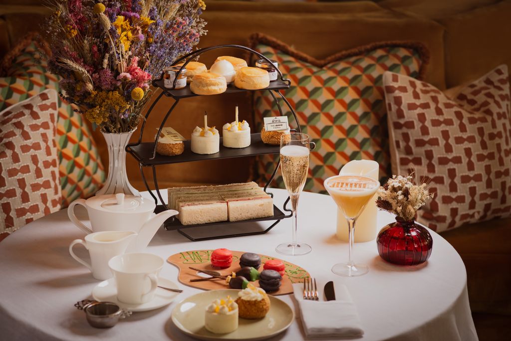 afternoon tea layed out on a table with dried flowers and cushions behind