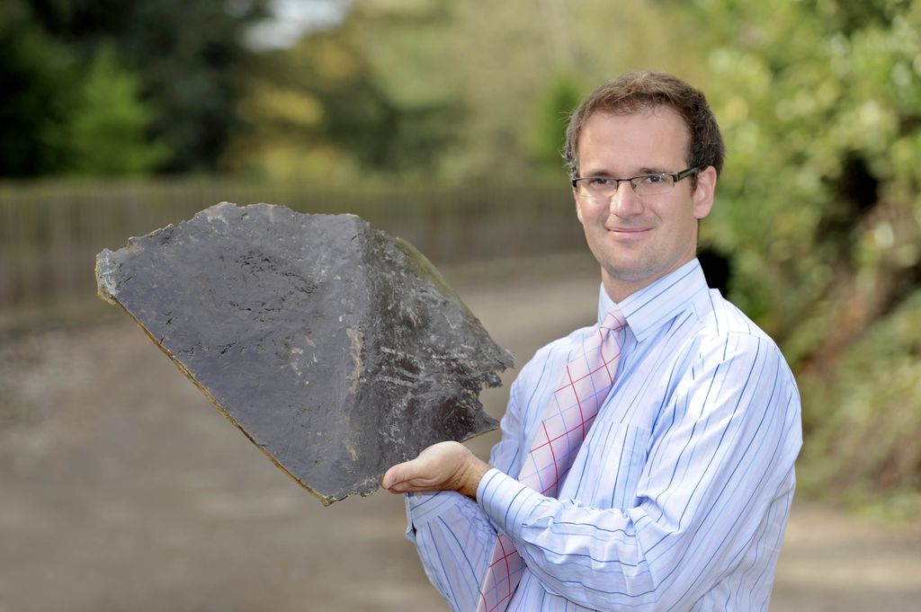 Man in suit holding large bronze slate