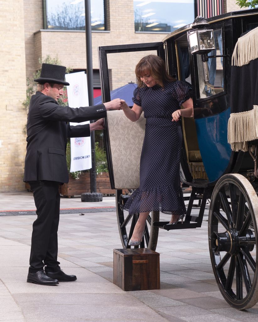 Lorraine Kelly steps out of a horse and carriage ahead of Coronation